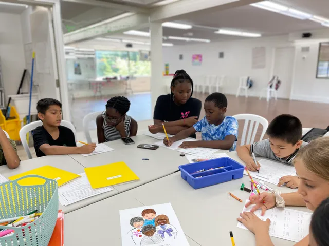 Children colouring and doing worksheets together at a table during a children's class