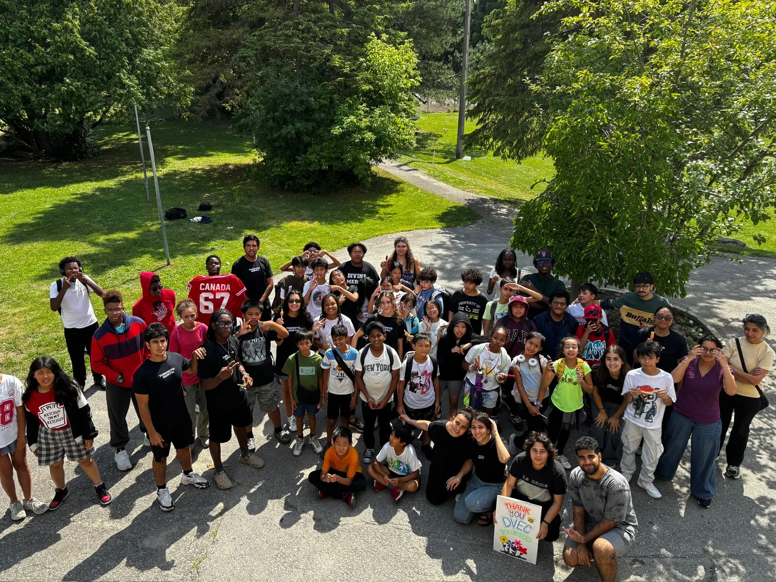 A large group of youth, junior youth, and volunteers gathered outdoors after a day of service