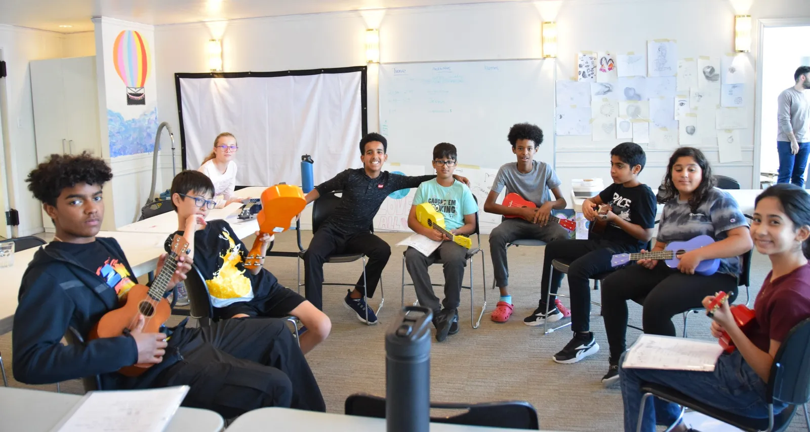 A junior youth group sitting in a circle playing ukuleles together